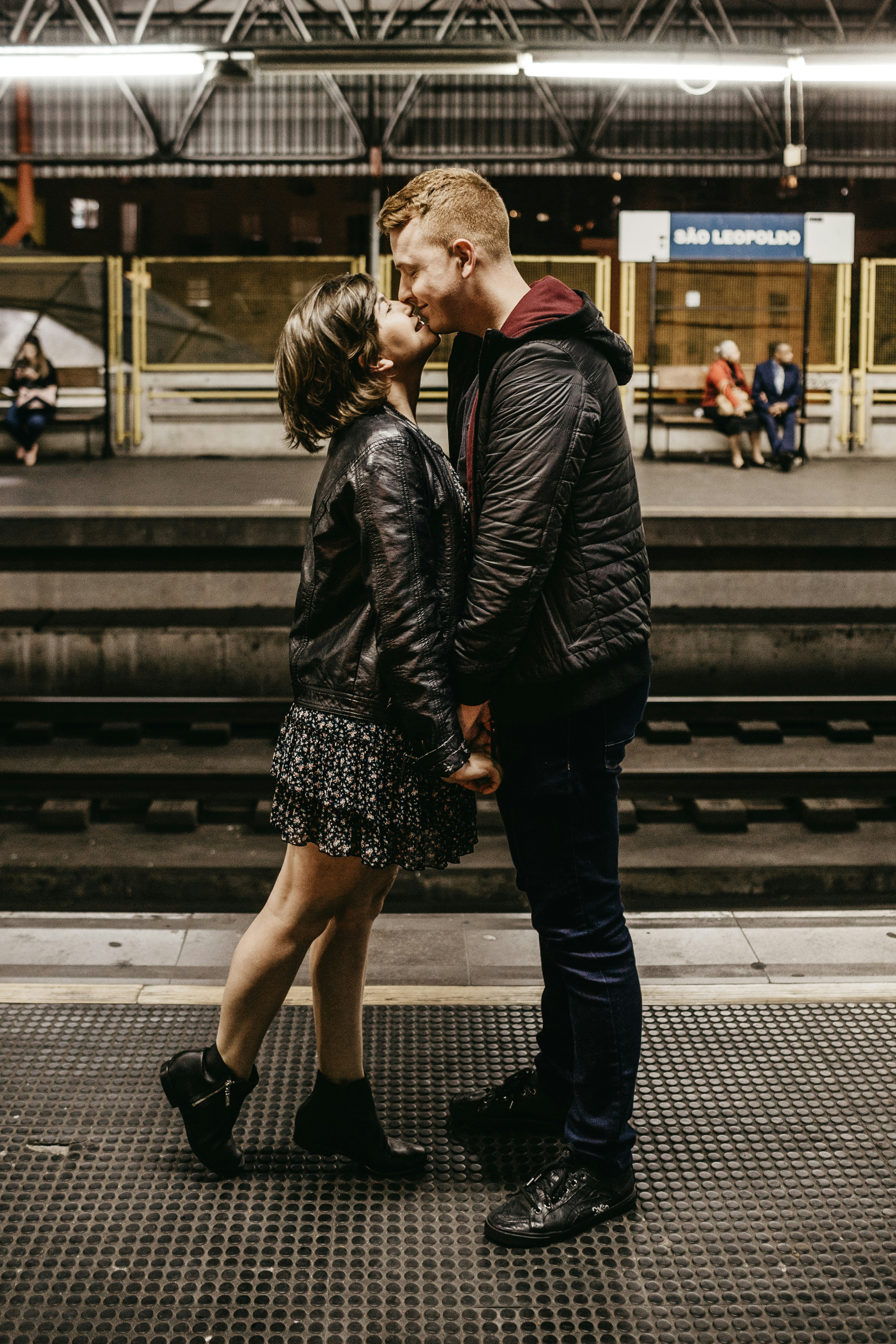 man and woman kissing beside train rails